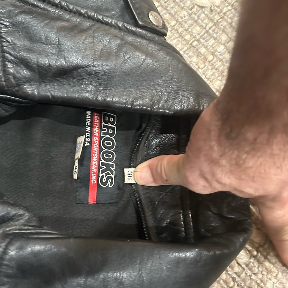 Black leather bikers jacket by Brooks. New $450. Size 36 missing buckle.